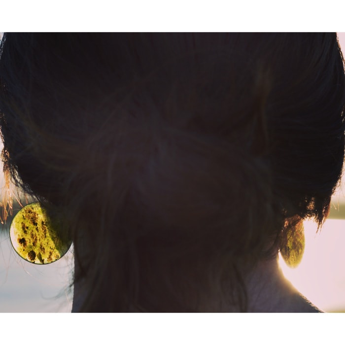 Small Tangiwai Pounamu Earrings Round on model with sun shining through