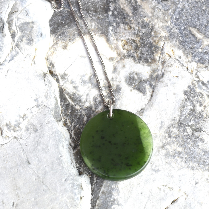 small bright green round pounamu pendant on silver chain